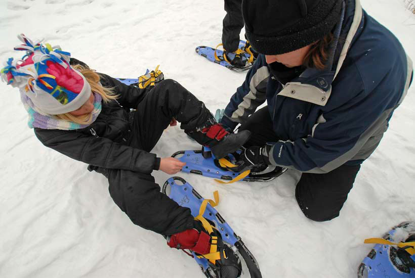Girl putting on snowshoes