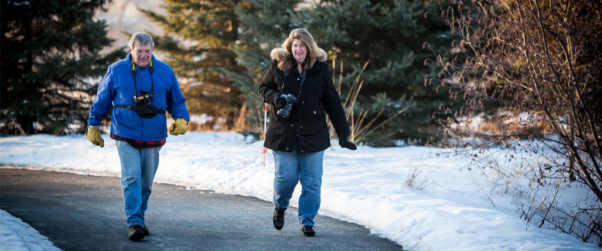 man and woman walking on paved path in winter