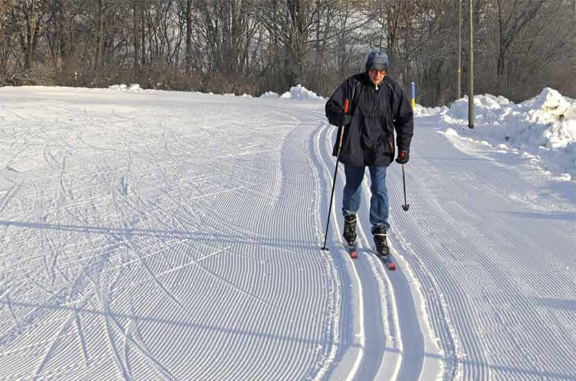 an older man doing classic cross-country skiing on a groomed trail.