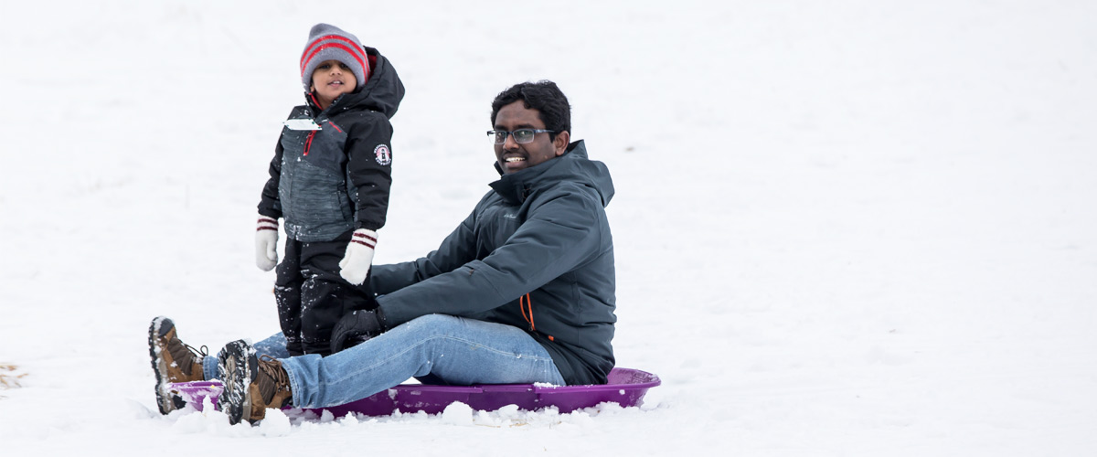 a dad and his son at the bottom of the sledding hill