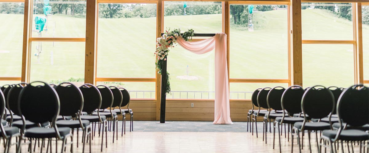 A room with tall windows set up for a ceremony.