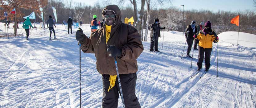 A person smiles while cross-country skiing through tracks in the snow.