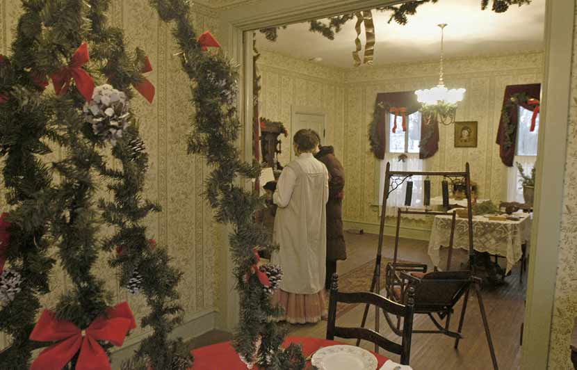 the setting of an 1800s house decorated in greenery for the December holiday season