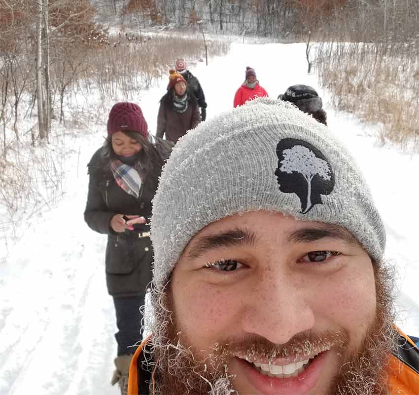 Winter selfie of Stephen with a frosty beard and four hikers on a snowy trail behind him.