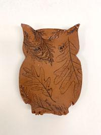 Photo of a clay animal plate shaped like an owl with leaf impressions.