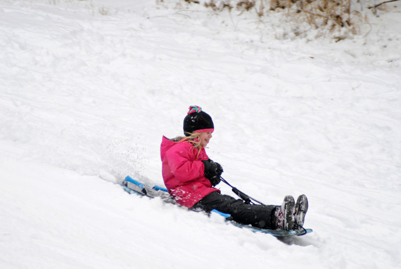 Girl sledding on hill
