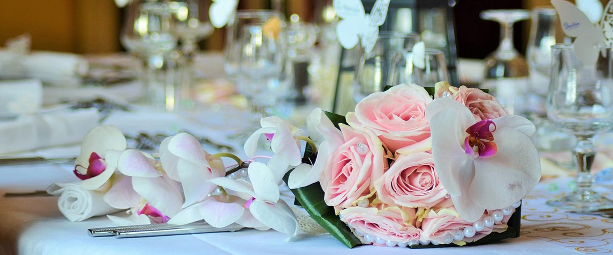 A bouquet of pink and white roses and orchids lying on a table.