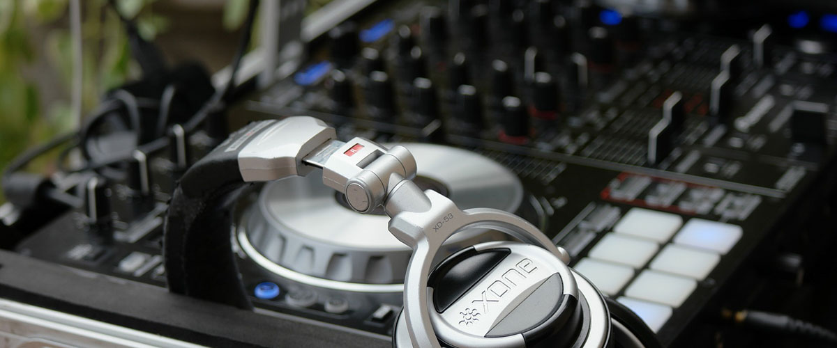 A pair of headphones lies next to DJ equipment.