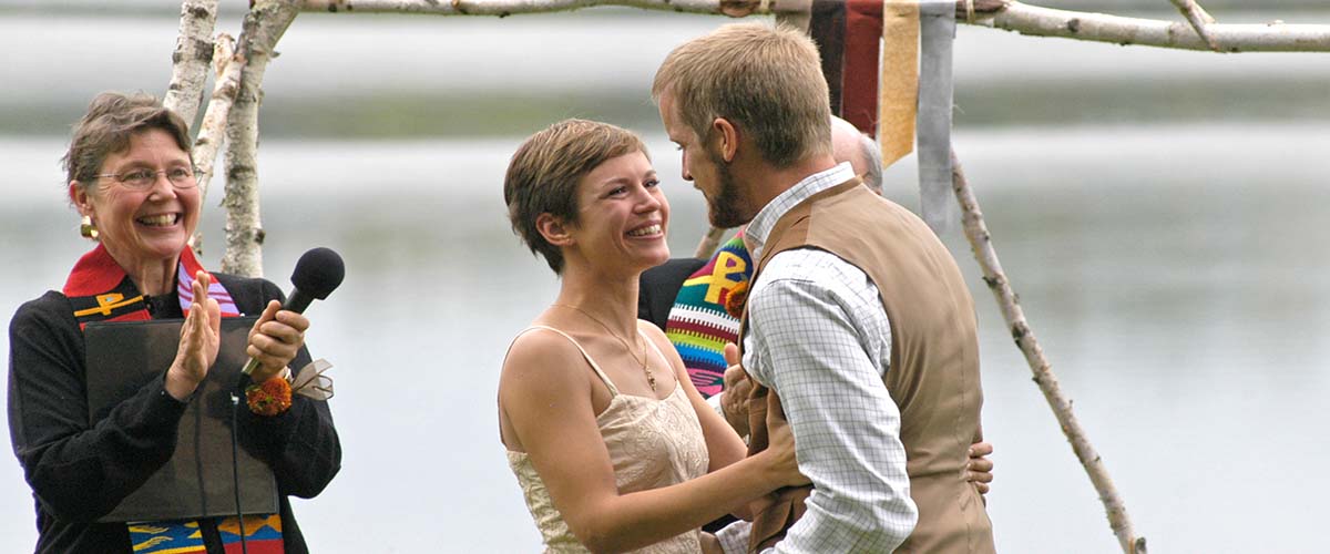 An officiant claps as a couple gets married.