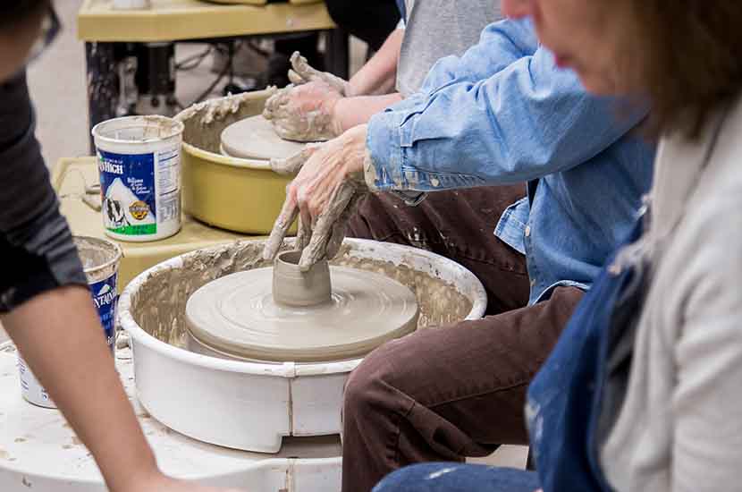A woman works clay on a potters wheel