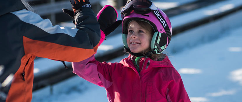 girl wearing ski helmet high-fiving an instructor