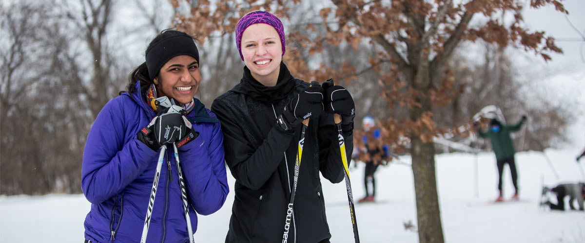 two women pose for picture holding ski poles