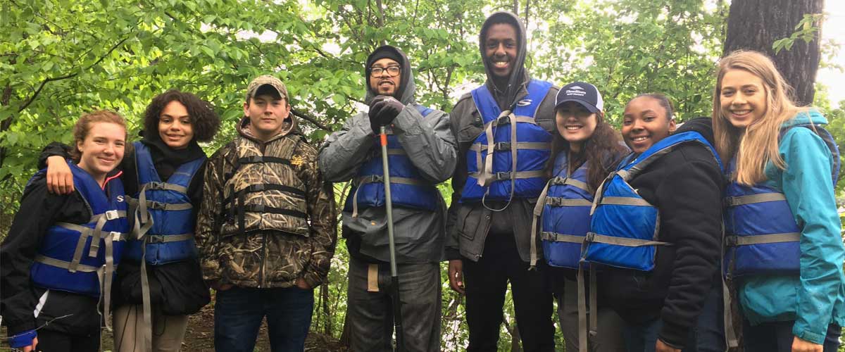 A group of interns with their arms around each other wearing life jackets