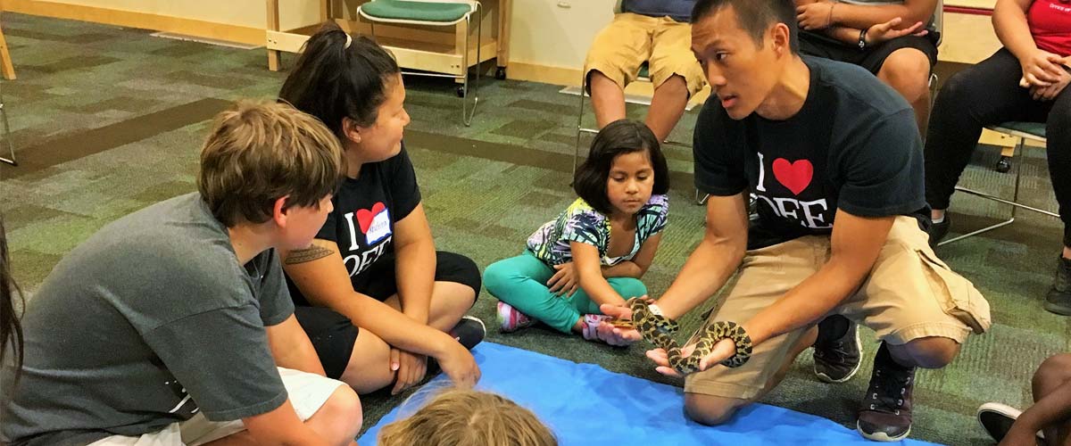 an intern showing a group of kids a snake.