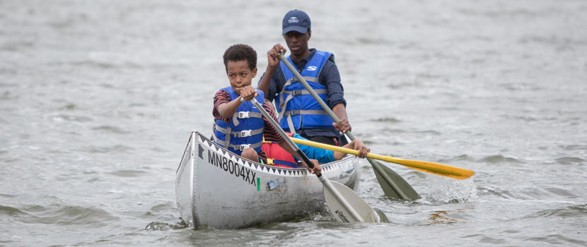 A pathways intern canoeing with a young boy.