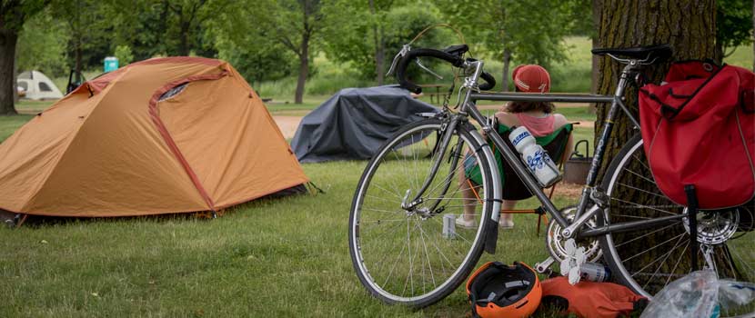 a bike leaning a tree with a tent in the background