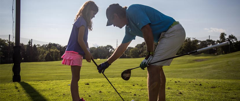 an instructor teaches a girl how to hold a golf club.