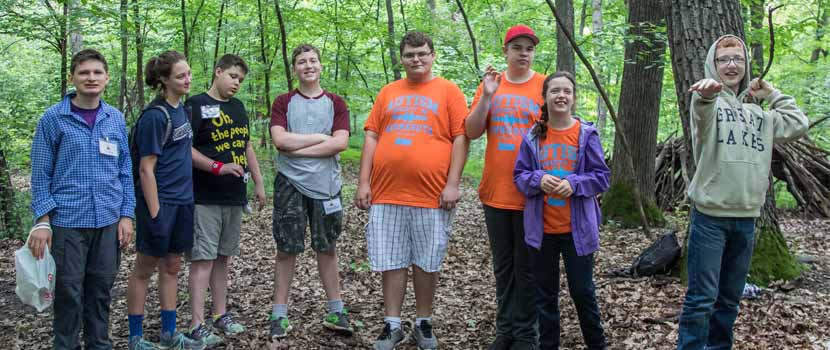 eight teens standing in the woods and smiling.
