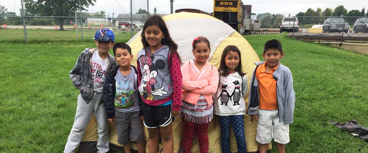 Six kids standing in front of a tent.