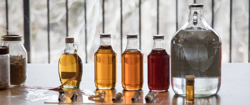Maple syrup of varying colors in glass jars.