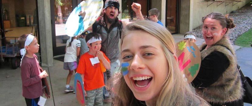 a teen taking a selfie with kids at camp.