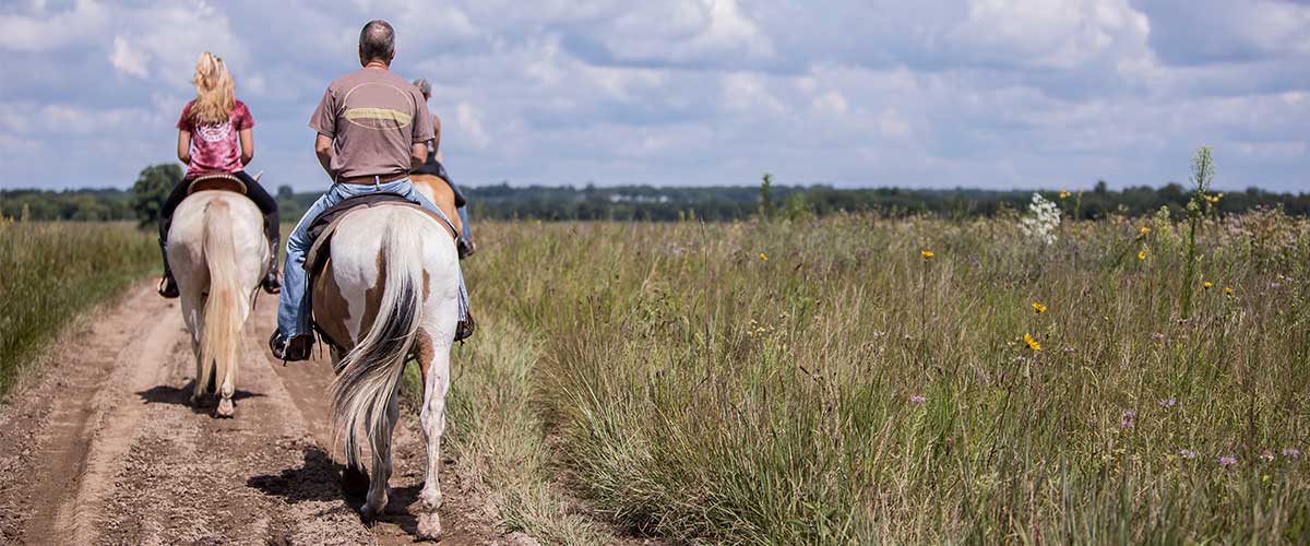 two people on horseback riding through the prairie