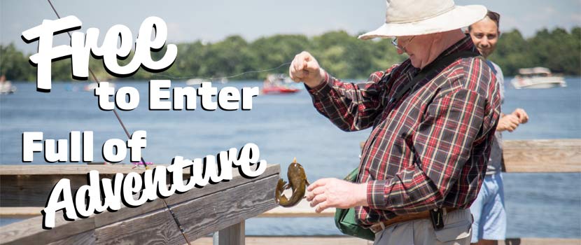 An older man reaches for a fish he caught from a wooden pier. Text on the left side of the image reads "Free to Enter, Full of Adventure."
