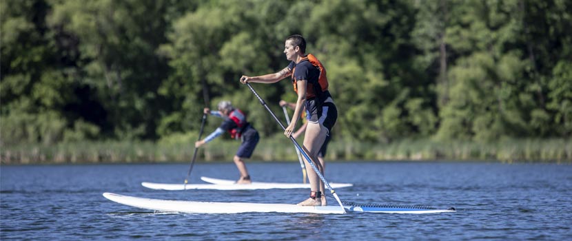A woman paddles a paddleboard on a lake.