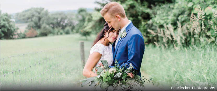 a bride and groom embraces in a pasture.