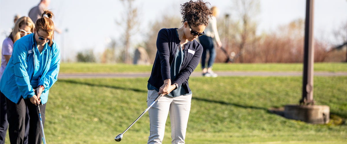 A woman practices golfing.