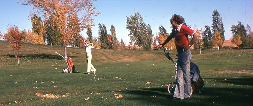 Two people play golf in the fall in the 70s.