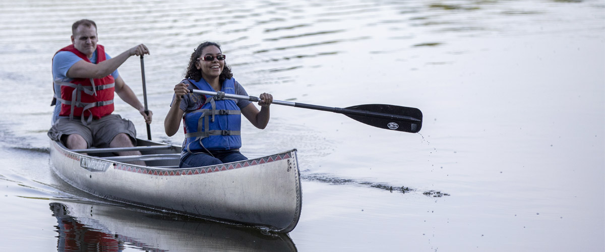 A man and woman paddle a canoe on a lake.