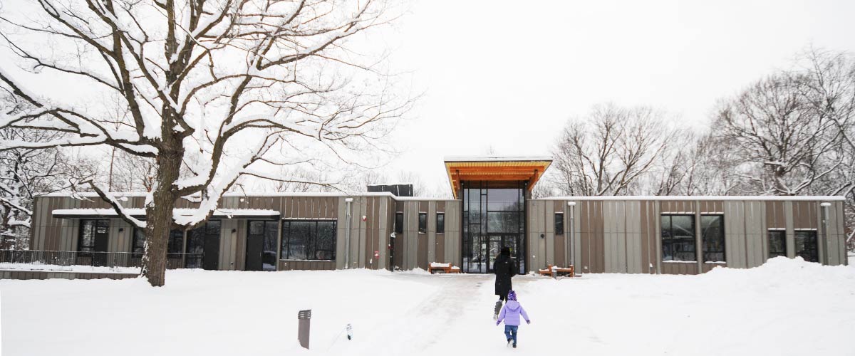 A nature center is nestled among trees in the snow.