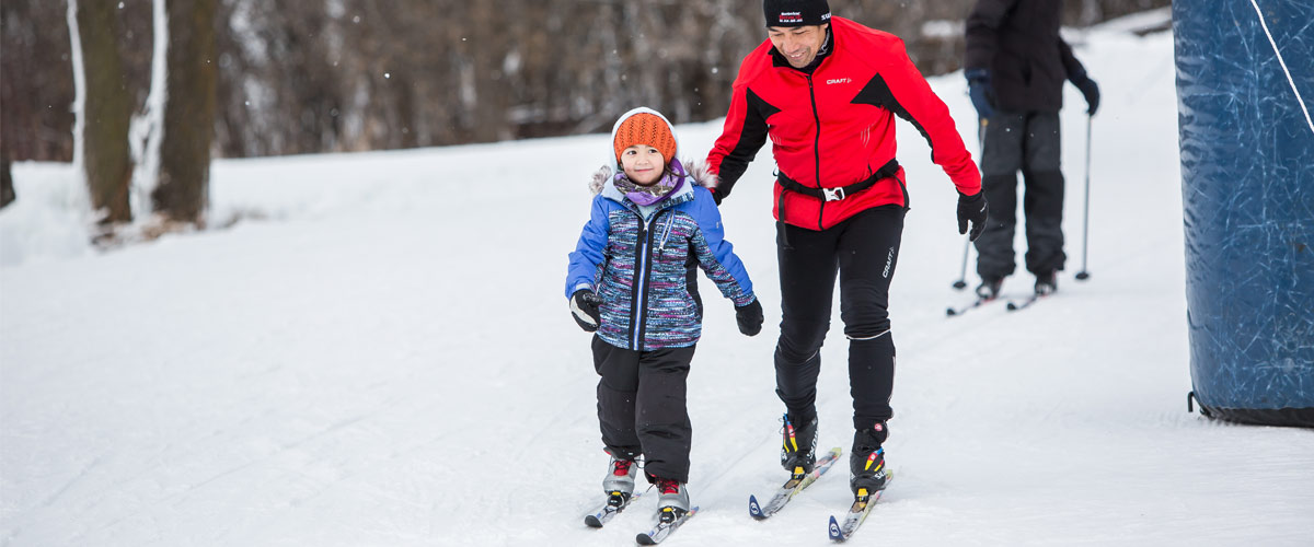 A man and his daughter cross-country ski.