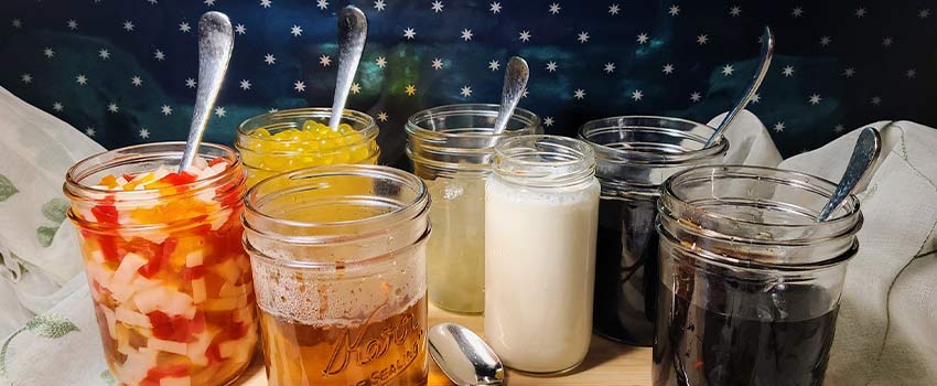 group of mason jars filled with boba tea toppings and spoons