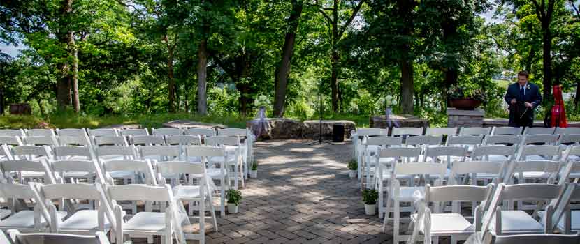 White chairs are set up for a ceremony on a patio at Silverwood Park. 
