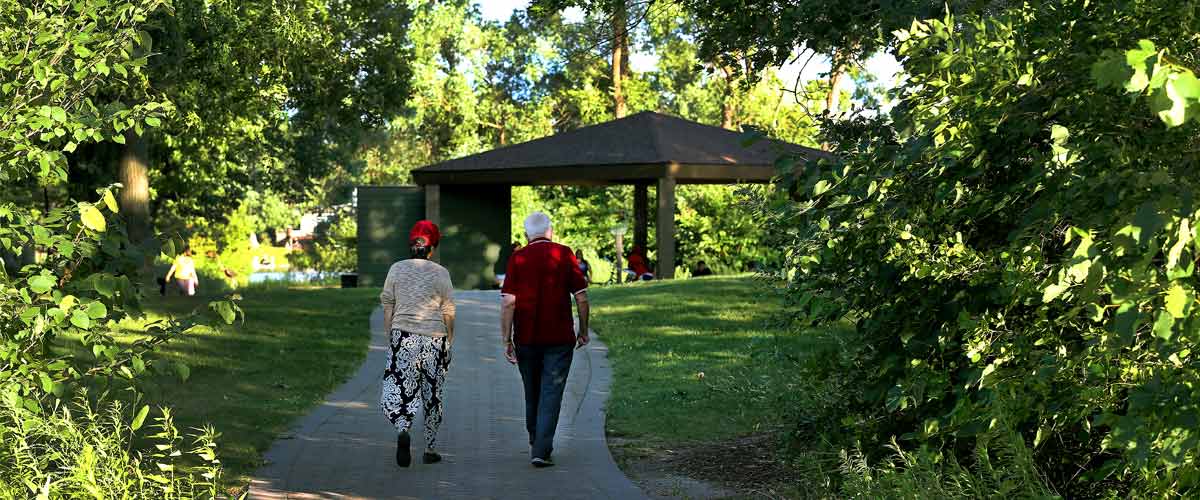 Two people walk down a path on Silverwood's island toward a picnic pavilion.