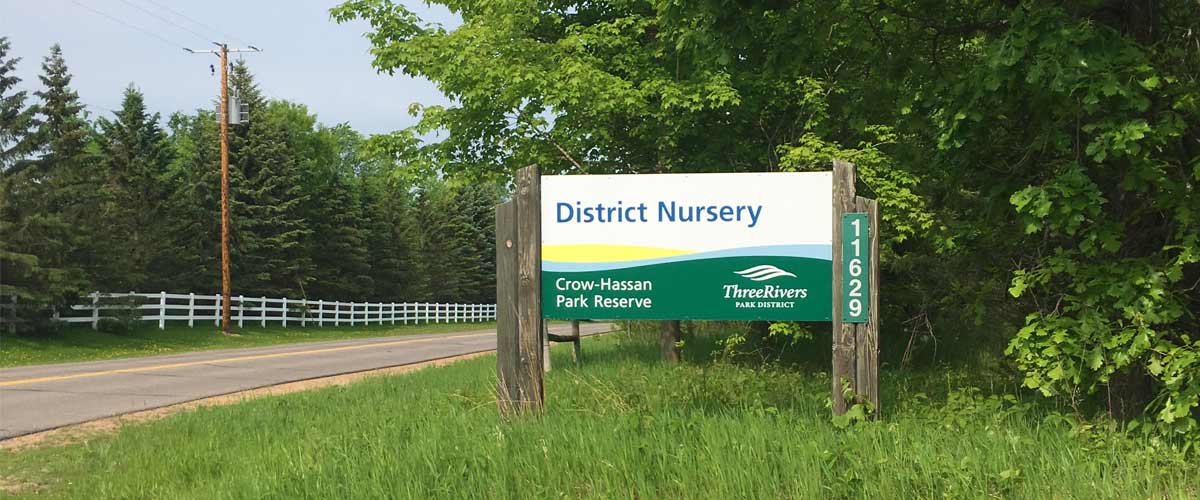 A sign that reads District Nursery stands along a road at the entrance to the Three Rivers Nursery.