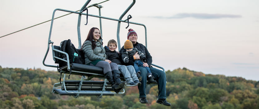 A family rides a chairlift in the fall at Hyland Hills.