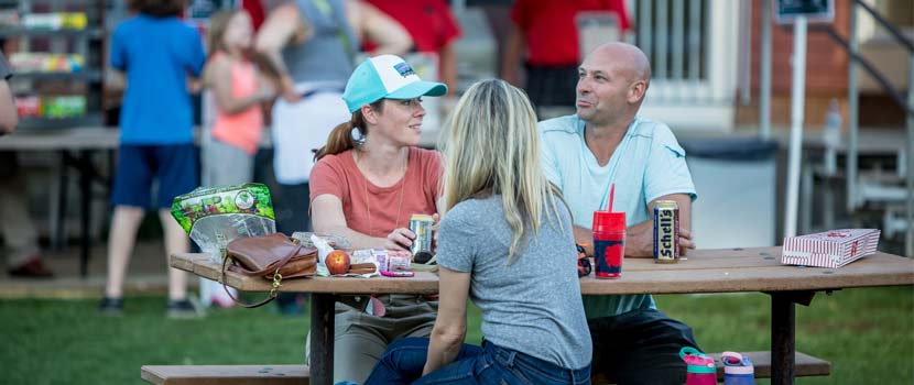 Three people enjoy happy hour at a picnic table at Hyland Hills.