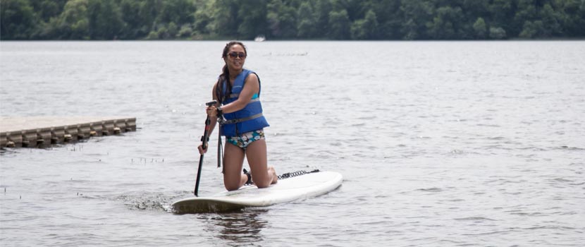 A woman paddles a stand-up paddleboard on a lake.