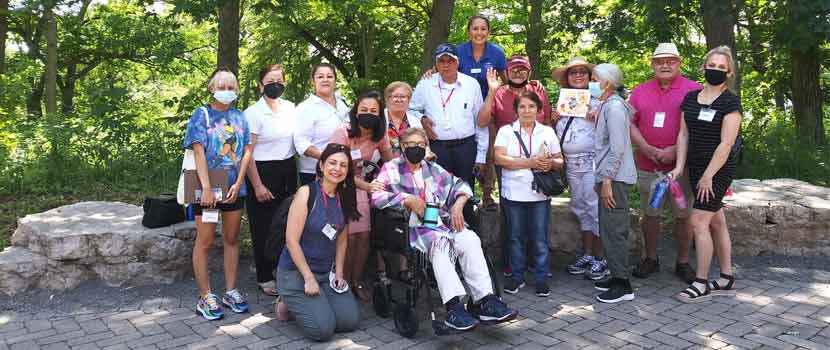 A group of Latino seniors poses for a photo on the outdoor patio at Silverwood Park.