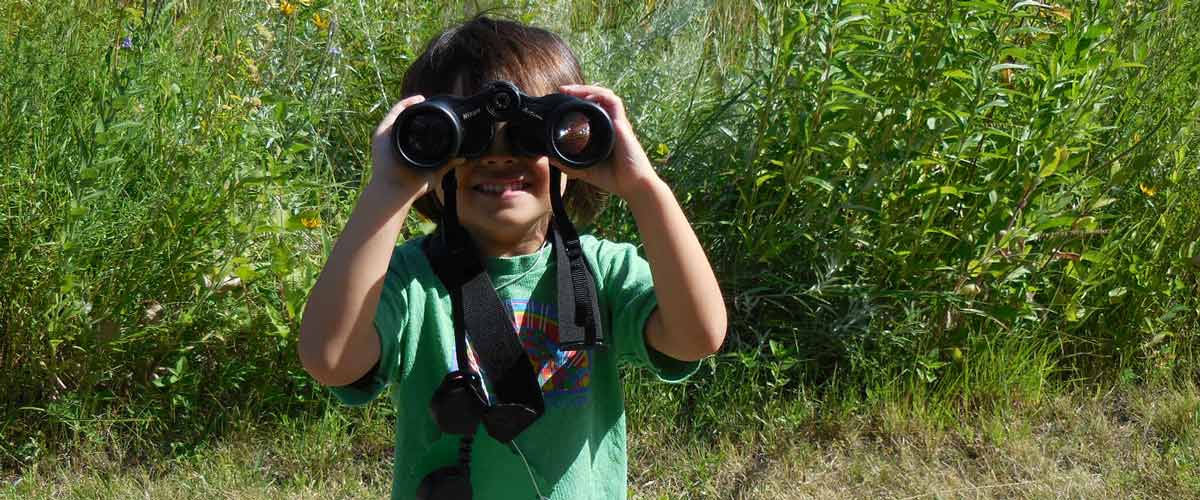A child looks out through a pair of binoculars.