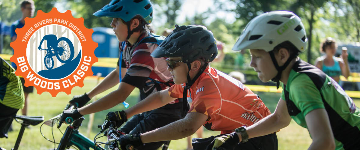 Three boys on bikes wearing mountain bike helmets get ready for a summer mountain bike race.