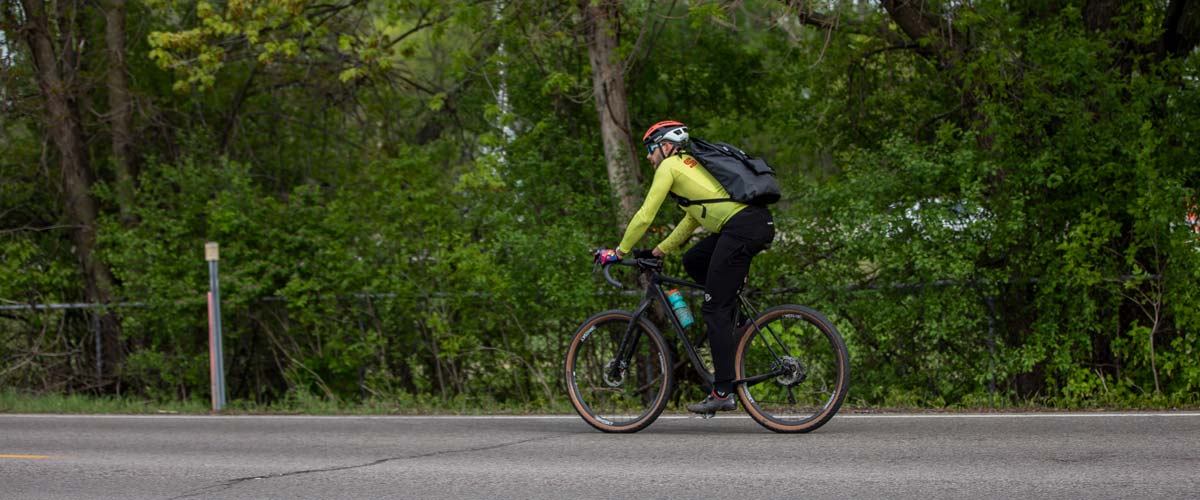 A person wearing a bike helmet, sunglasses and backpack while cycling on the regional trail.