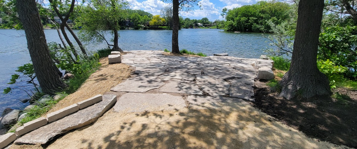 a view looking out at Silver Lake with stone pavers that were installed on land