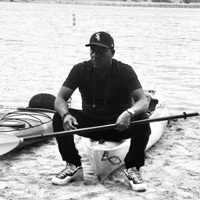 Farji sits on a canoe holding a paddle.