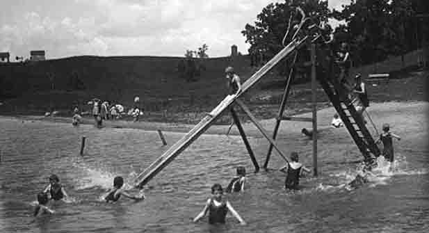 Photo of campers sliding down a slide into the lake at the Silver Lake Camp. Photo courtesy of the Minnesota Historical Society.