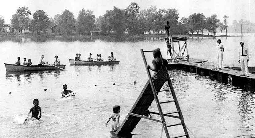 Photo from Three Rivers photo archive showing campers swimming, canoeing and fishing in the lake.