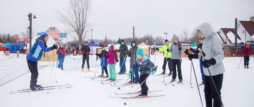 An instructor teaches a group of people how to cross-country ski.
